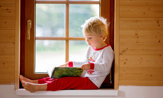 Boy reading a Halloween book by the window